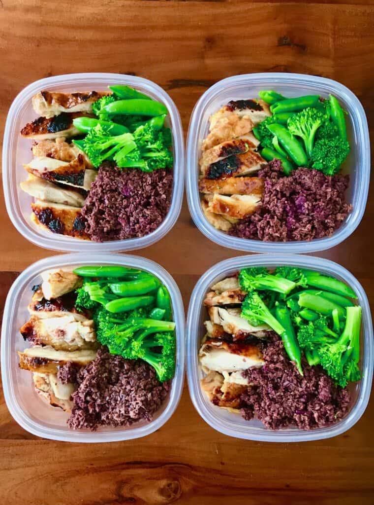 Soy free teriyaki chicken sliced next to purple sweet potato rice and sugar snap peas and broccoli in Tupperware containers.