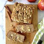 A loaf of healthy apple bread on a cutting board with two slices.