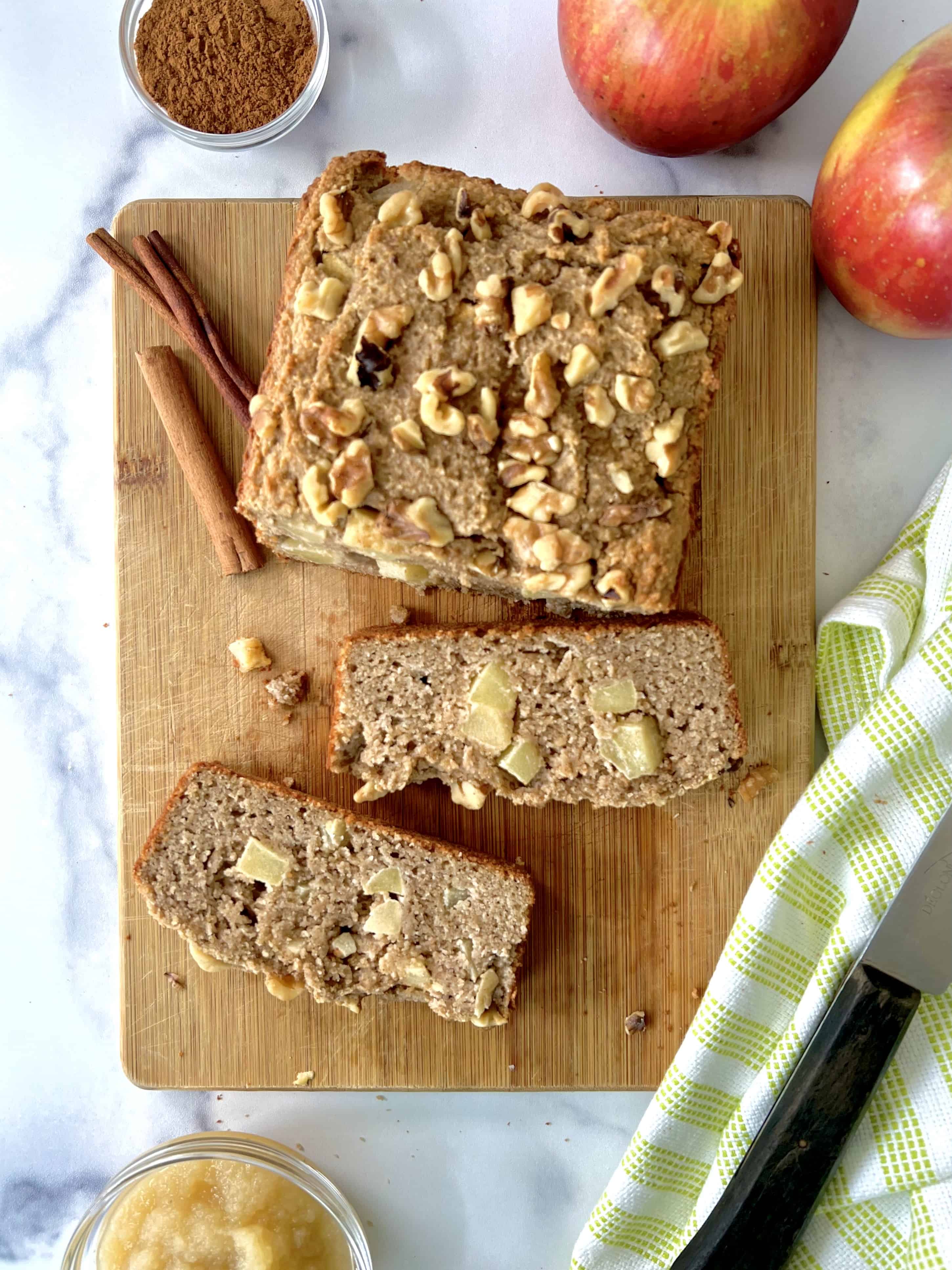 A loaf of healthy apple bread on a cutting board with two slices.