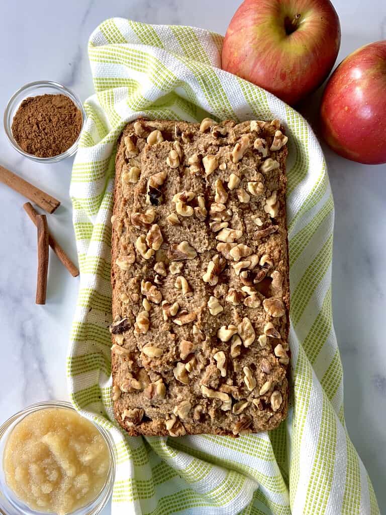 A loaf of gluten-free apple bread with almond flour on a towel.
