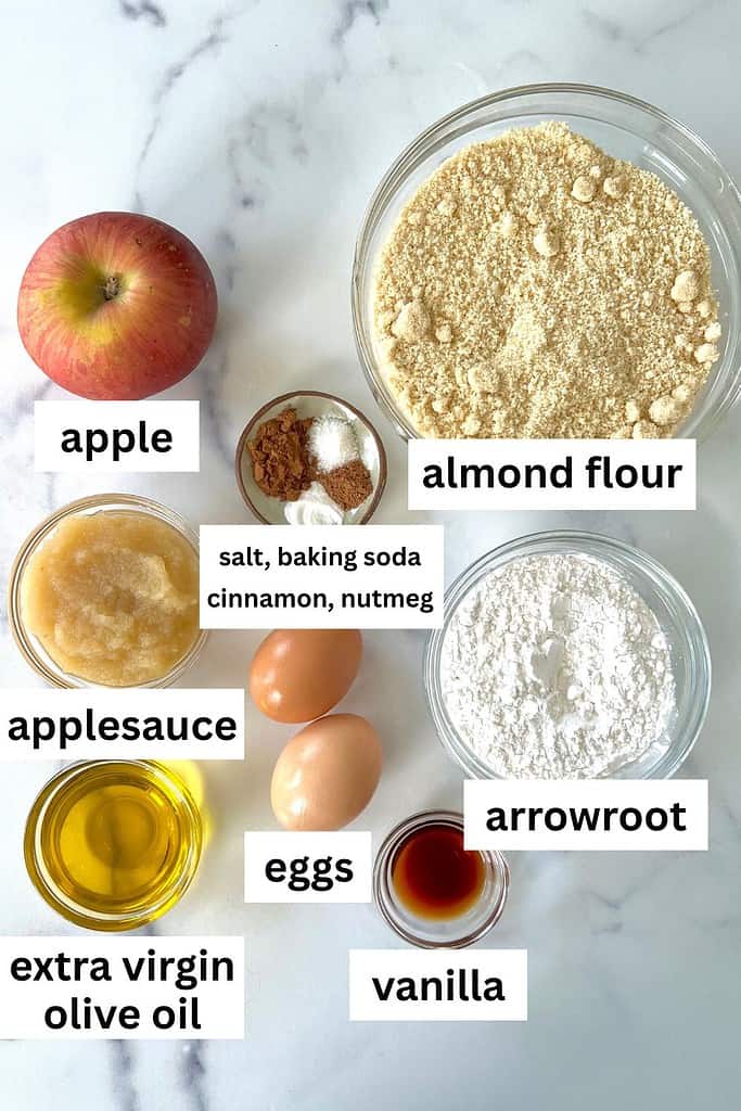 The individual ingredients for Almond Flour Apple Bread in separate bowls on a marble surface.