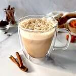 An almond milk pumpkin spice latte in a glass mug.