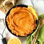 Vegan mashed sweet potatoes with ginger and orange in a bowl garnished with orange slices.