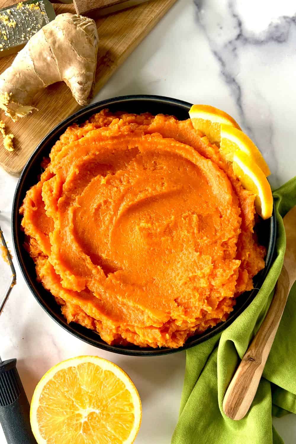 Mashed sweet potatoes with ginger and orange in a bowl garnished with orange slices.