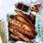 Dairy-free biscotti piled into a towel-lined square tin.