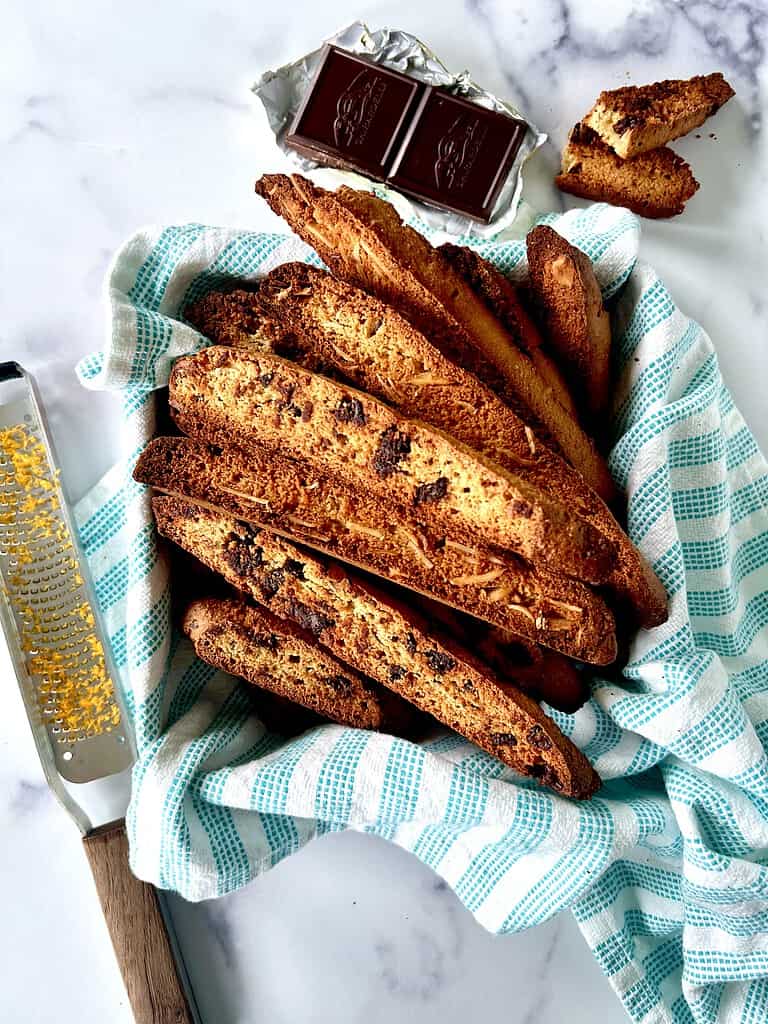 Dairy-free biscotti piled into a towel-lined square tin.
