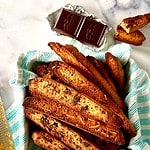 Paleo biscotti piled into a towel-lined square tin.