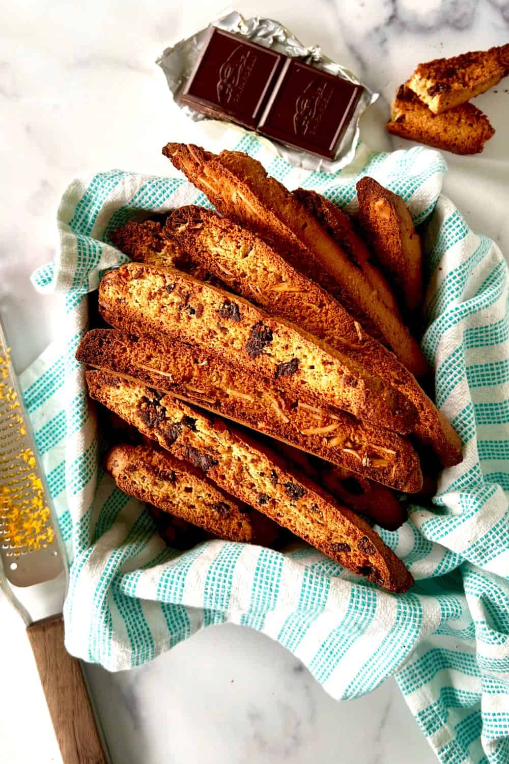 Paleo biscotti piled into a towel-lined square tin.